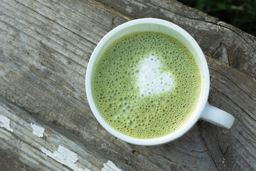 Cup of matcha latte on a textured wooden surface