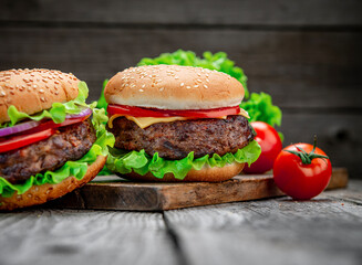 Two delicious homemade burgers of beef on an old wooden table. Fat unhealthy food close-up.