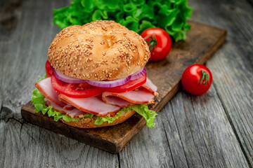 Sandwich with ham and vegetables on an old wooden table