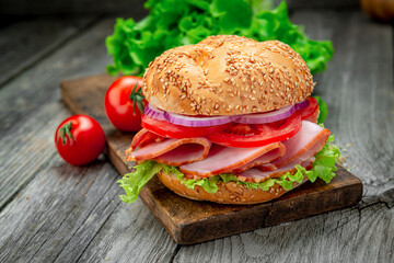 Sandwich with ham and vegetables on an old wooden table