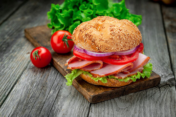 Sandwich with ham and vegetables on an old wooden table
