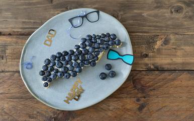 Moustache-shaped cake with blueberries and decoration. Copy space.