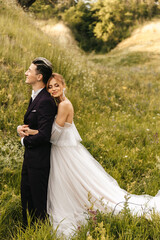 The bride hugs a stylish handsome groom. Beautiful couple in nature against the background of the hills