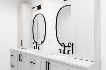A luxury bathroom with a grey double vanity cabinet, black faucets and lights, and a white marble...
