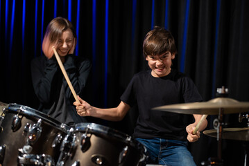 Fototapeta na wymiar Young woman teaching boy to play drums.