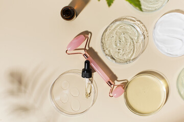 Homemade cosmetics for skincare and quartz face roller on beige background