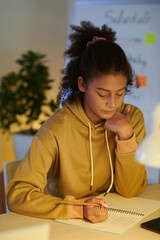 School student doing homework at her desk late at night