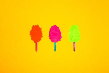 three paper ice creams on a stick, orange, pink and green on a yellow background, summer modern...