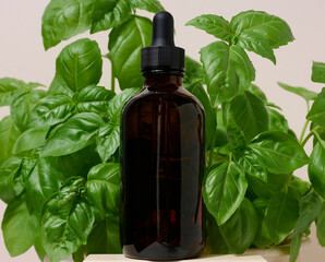 Brown glass bottle with a pipette against the background of green basil leaves