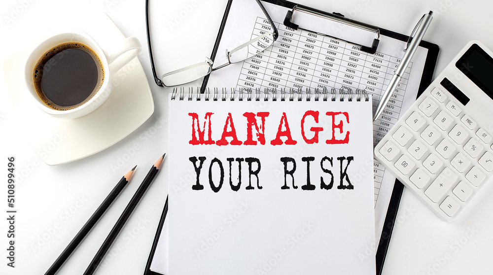 Poster manage your risk text on the paper with calculator, notepad, coffee ,pen with graph