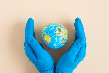 Earth globe in hands in blue protective glove on a clean. The concept of protecting nature, ecology...