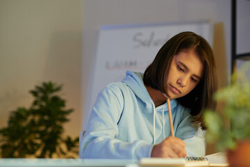 Schoolgirl concentrated on studying and revising information for exam at home