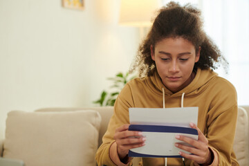 Anxious teenage girl opening acceptance letter from university