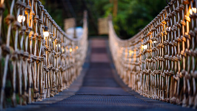 Fototapeta rope bridge decorated with warming bulb light at twilight evening