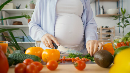 Obraz na płótnie Canvas Beautiful Pregnant Woman Happily Preparing a Vegetable Salad, Organic Healthy Food, in a Cozy Home Kitchen. The Concept Of Diet, Proper Nutrition, Healthy Pregnancy and People.