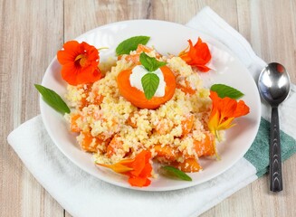 Sweet millet porridge with apricots. Healthy puree of millet grains, apricot and coconut for a snack. Decorated with edible flowers of nasturtium.