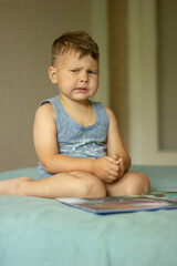 The boy sitting on the bed shows emotionally that he is unhappy and sad