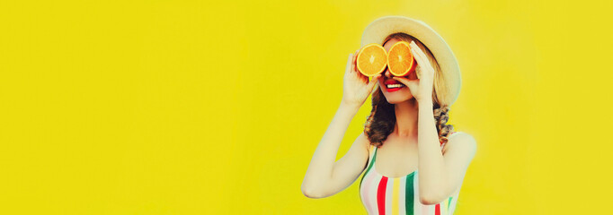 Summer portrait of happy cheerful smiling woman covering her eyes with slices of orange and looking...