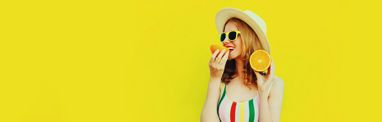 Summer portrait of young woman eating fresh slices of orange fruits wearing straw hat, sunglasses...