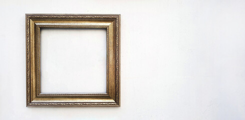 Golden or brown picture frame mockup on white concrete wall with copy space. Framework isolated on...