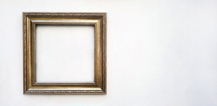 Golden or brown picture frame mockup on white concrete wall with copy space. Framework isolated on background.