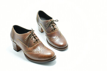 Zapatos de cuero color cafe. Calzado de tacon bajo sobre fondo blanco, espacio para texto al lado derecho.