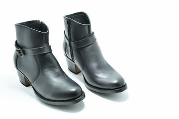 Botines de cuero color negro. Calzado de tacon bajo sobre fondo blanco, espacio para texto al lado derecho.