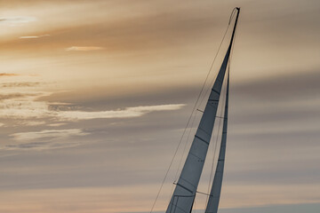 Top of mast of sailing yacht at sunset, orange sky, sail regatta, magic clouds sky