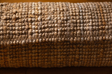 New rolled jute rug with chunky texture on oak flooring, natural fiber carpet, eco friendly home interior concept, shallow DoF