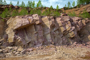 A section of crimson quartzite rock in an old quarry. Kvartsitny village, Karelia - obrazy, fototapety, plakaty