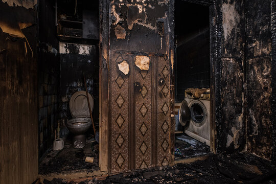 Burnt house interior. Fused remains of furniture and washing machine.