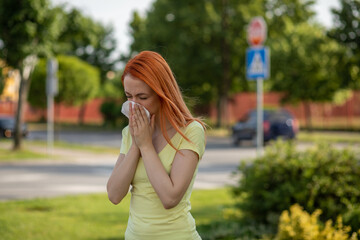 Fototapeta premium Young redhair woman sneezing in spring. Pollen Allergy symptoms