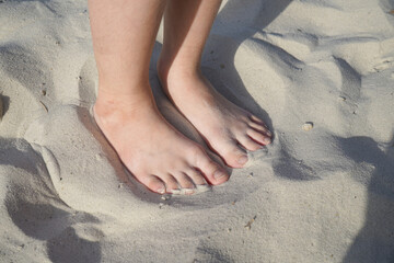 Two bare children's feet close-up on the sand