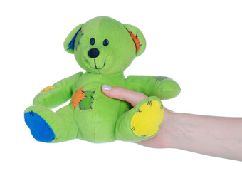 Green small soft toy bear in hand on white background isolation