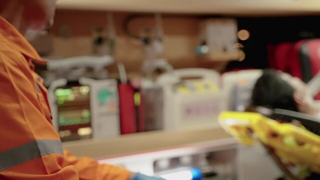 Asian paramedic worker is sitting in a car to pick up a patient with a tense expression on his face and anxious
