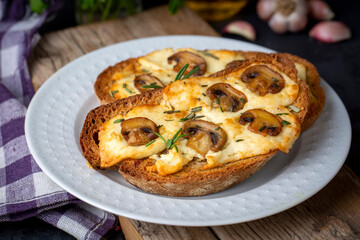 Obraz na płótnie Canvas Toasted sandwich from traditional sourdough bread with cheese and brown mushrooms seasoned with rosemary herb on a wooden board, top view