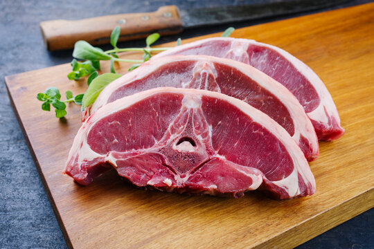 Rohe Lammr&uuml;ckensteaks mit Kr&auml;utern angeboten als close-up auf einem Holz Design Board 