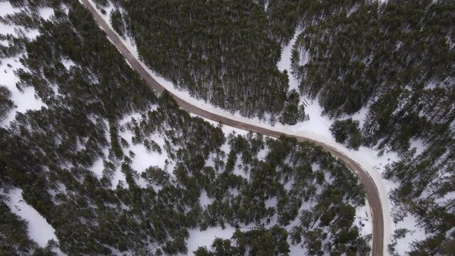 Winding Road In Winter Landscape. Aerial view from drone of road among trees in snowy forest.