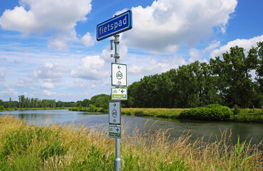 Maasvallei, Limburg, Netherlands - Juin 9. 2022: Dutch bike route junction with direction signs, rural landscape river Maas background