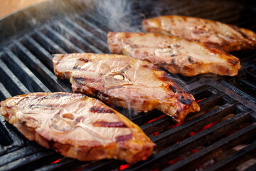Barbecue Lammrückensteaks gegrillt als close-up auf einem Holzkohlegrill mit Feuer