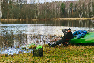 Obraz na płótnie Canvas A man resting and fishing on the shore of a lake, fishing for pike, perch, carp, the concept of rural recreation