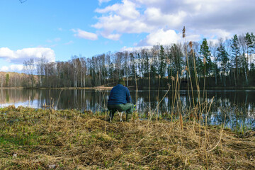 Obraz premium Fisherman with a fishing rod, spinning reel on the river bank, fishing for pike, perch, carp