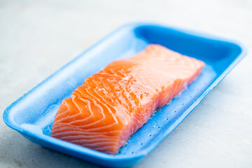 Fresh raw salmon in plastic container, close up view.
