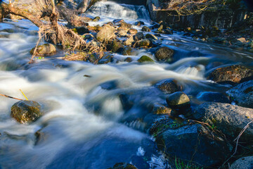 Fototapeta na wymiar rapid river flow between rocks, water white as milk, long-term exposure