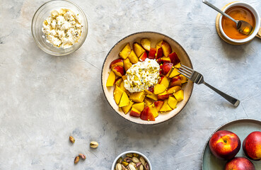 Healthy fruit salad with nectarine, ricotta cream with pistachios and honey, Top view. Copy space