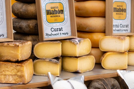 Barcelona, Spain - May 15, 2020. Street market stall with Mahón cheese, made with cow's milk. Uncooked pressed paste, with parallelepiped shape and rounded edges.
