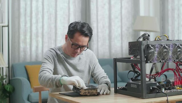 Asian Man Wearing Glasses Wiping The Mining Rig For Mining Cryptocurrency 
