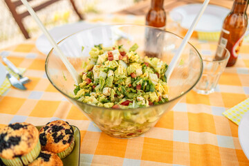 Fresh vegetable salad in a glass bowl on a checkered tablecloth on the veranda