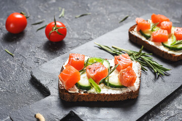 Healthy toasts with rye bread with cream cheese, salmon, fresh cucumber and sesame seeds.