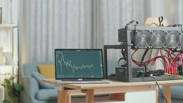 A Laptop Showing Bitcoin Chart Is On The Table With Cryptocurrency Mining 
